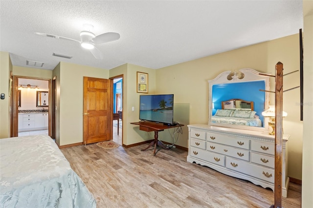 bedroom with a textured ceiling, ensuite bath, light hardwood / wood-style floors, and ceiling fan