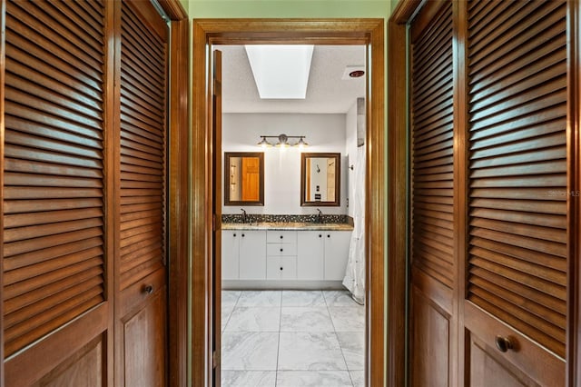 bathroom featuring vanity, a skylight, and a textured ceiling