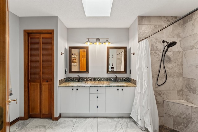 bathroom with vanity, a skylight, a textured ceiling, and walk in shower