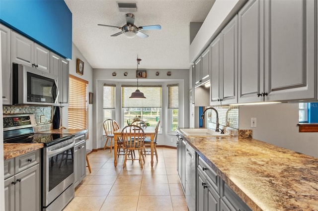 kitchen with sink, gray cabinetry, a textured ceiling, light tile patterned floors, and appliances with stainless steel finishes