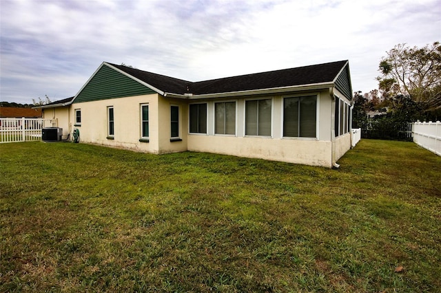 rear view of property with central AC and a lawn