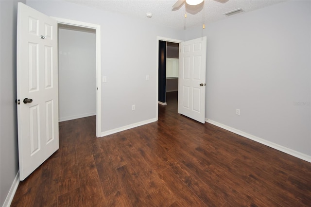 unfurnished bedroom with a textured ceiling, dark wood-type flooring, and ceiling fan