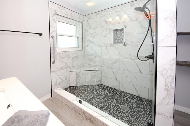 bathroom with hardwood / wood-style flooring and a tile shower