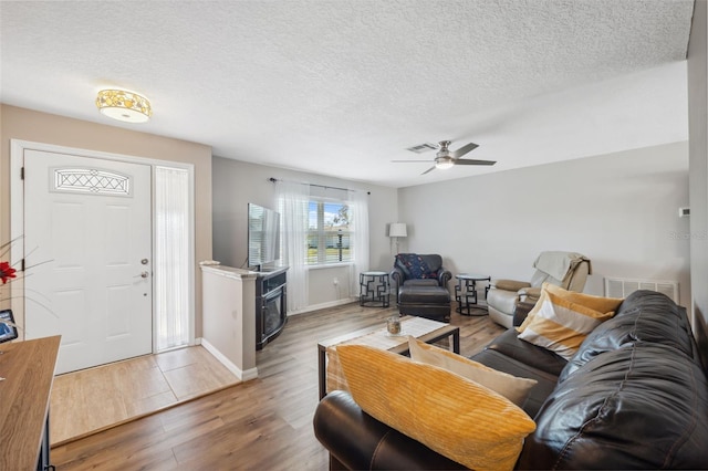 living room with ceiling fan, hardwood / wood-style floors, and a textured ceiling