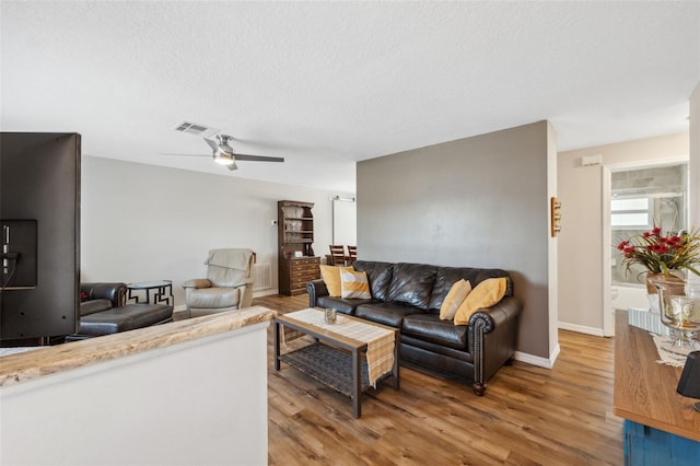 living room with hardwood / wood-style flooring, ceiling fan, and a textured ceiling