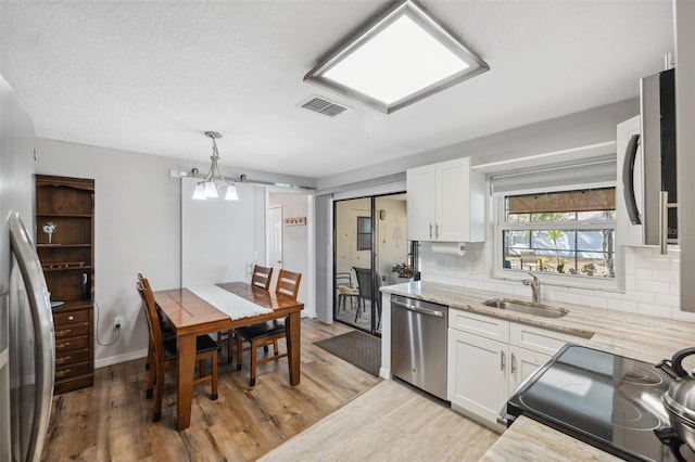 kitchen with appliances with stainless steel finishes, decorative light fixtures, sink, and white cabinets