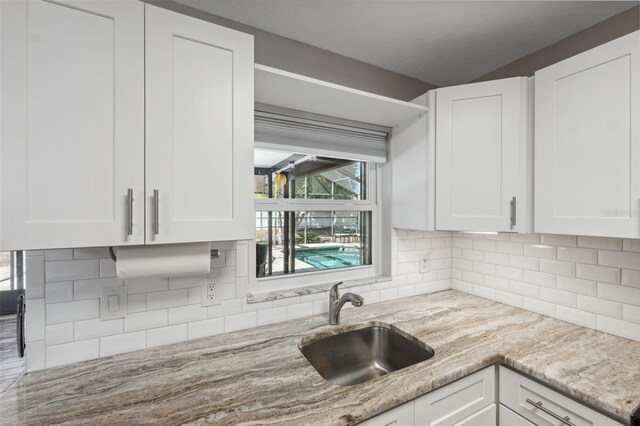 kitchen featuring sink, white cabinets, and light stone counters