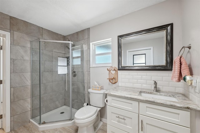 bathroom with toilet, vanity, backsplash, and walk in shower