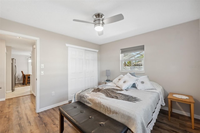 bedroom with hardwood / wood-style flooring, stainless steel fridge, a closet, and ceiling fan