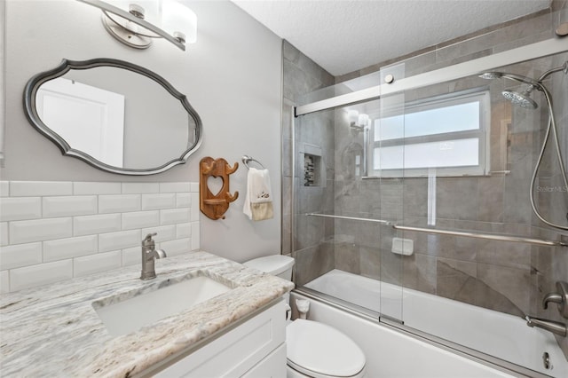 full bathroom with bath / shower combo with glass door, decorative backsplash, vanity, toilet, and a textured ceiling