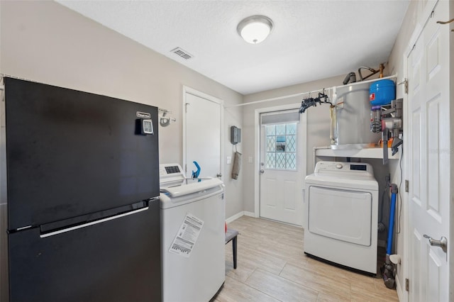 washroom featuring washing machine and clothes dryer, a textured ceiling, and light hardwood / wood-style floors