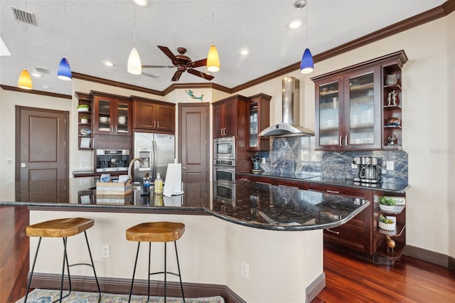 kitchen featuring pendant lighting, wall chimney exhaust hood, and stainless steel appliances