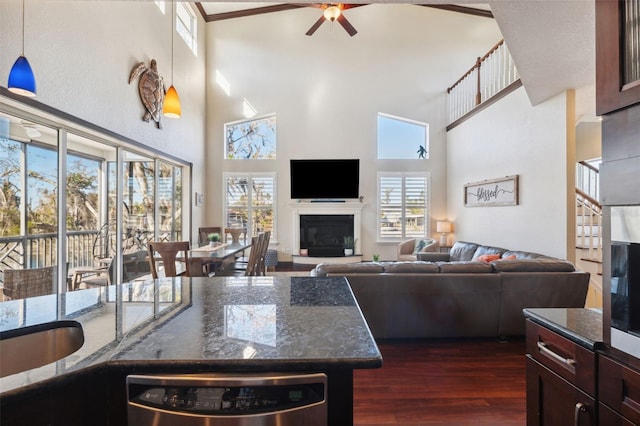 living room featuring ceiling fan, ornamental molding, dark hardwood / wood-style flooring, and a towering ceiling