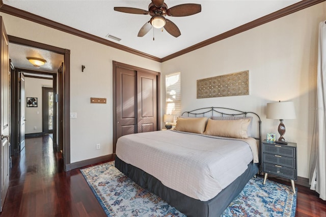 bedroom with ornamental molding, dark wood-type flooring, ceiling fan, and a closet