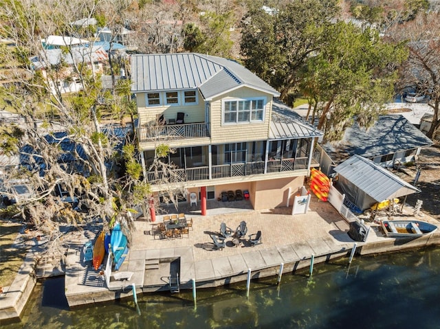 back of property featuring a water view, a patio area, a sunroom, and an outdoor fire pit