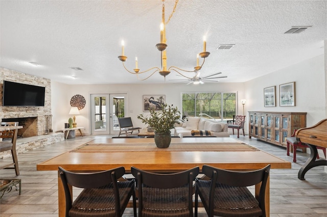 dining space with light hardwood / wood-style flooring, a fireplace, french doors, and a healthy amount of sunlight