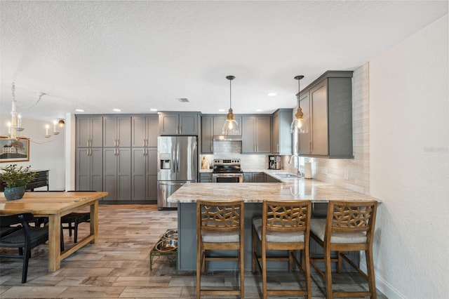 kitchen with gray cabinets, appliances with stainless steel finishes, sink, hanging light fixtures, and kitchen peninsula