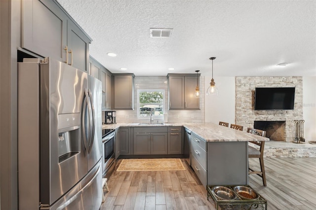 kitchen with sink, a breakfast bar area, kitchen peninsula, pendant lighting, and stainless steel appliances