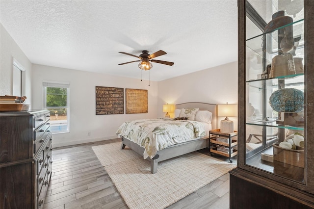 bedroom with ceiling fan, light hardwood / wood-style floors, and a textured ceiling