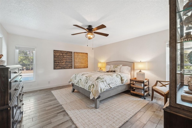 bedroom with ceiling fan, wood-type flooring, and a textured ceiling