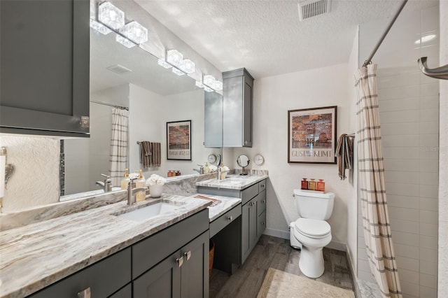 bathroom featuring toilet, a shower with curtain, wood-type flooring, a textured ceiling, and vanity