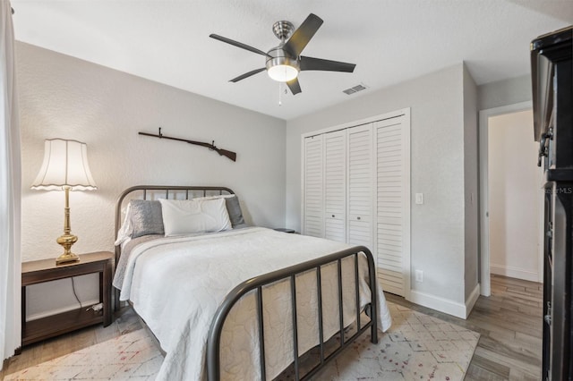 bedroom with ceiling fan, light hardwood / wood-style floors, and a closet