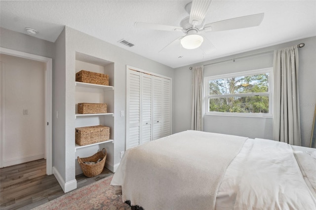 bedroom featuring a textured ceiling, dark wood-type flooring, a closet, and ceiling fan