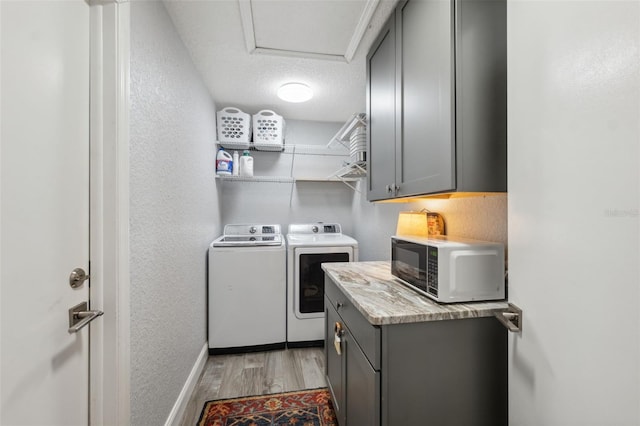 washroom with cabinets, a textured ceiling, washer and clothes dryer, and light hardwood / wood-style flooring