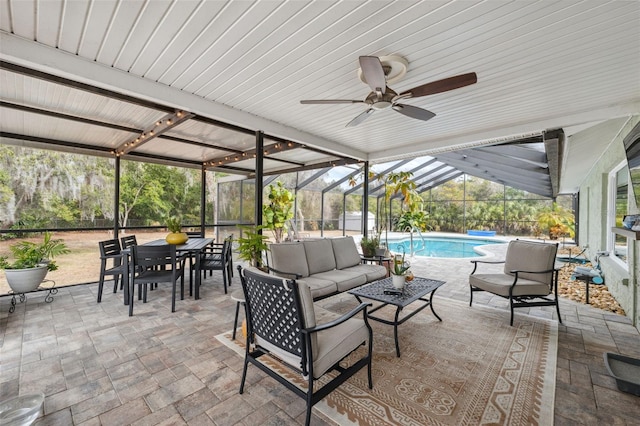 view of patio featuring outdoor lounge area, ceiling fan, and glass enclosure