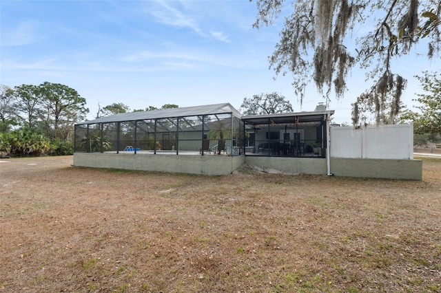 rear view of property featuring a lanai and a yard