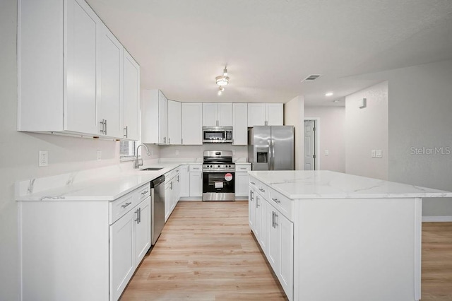 kitchen with white cabinetry, appliances with stainless steel finishes, sink, and a kitchen island