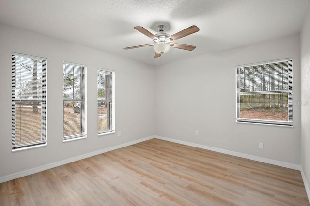 spare room featuring ceiling fan, light hardwood / wood-style flooring, and a wealth of natural light