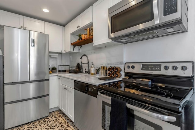 kitchen with stainless steel appliances, sink, white cabinets, and light stone counters