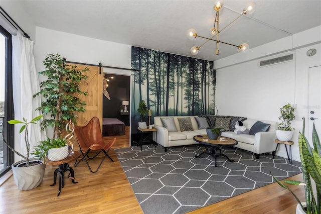 living room featuring dark hardwood / wood-style floors, a barn door, and an inviting chandelier