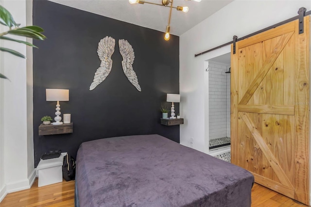 bedroom featuring a barn door and light wood-type flooring