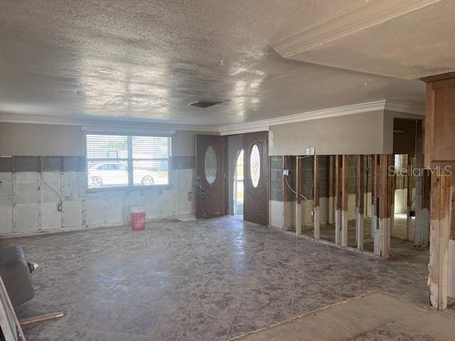 foyer with ornamental molding and a textured ceiling