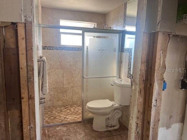 bathroom featuring toilet and a shower with door