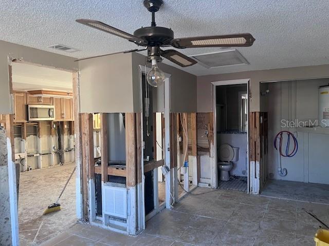 miscellaneous room with ceiling fan and a textured ceiling