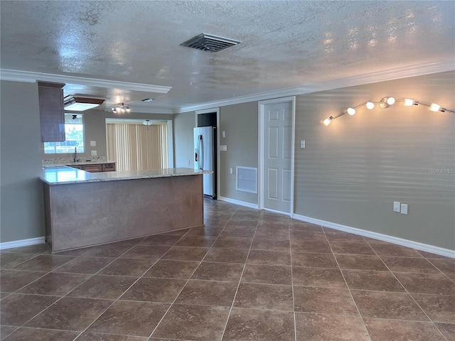 13637 Lagoon Dr, Hudson, FL 34667 - kitchen with visible vents, ornamental molding, a textured ceiling, and stainless steel fridge
