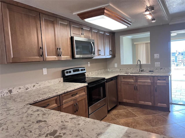 13637 Lagoon Dr, Hudson, FL 34667 - kitchen with dark tile patterned floors, a textured ceiling, appliances with stainless steel finishes, a sink, and light stone counters