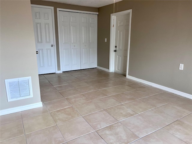 13637 Lagoon Dr, Hudson, FL 34667 - unfurnished bedroom with baseboards, visible vents, light tile patterned floors, and a closet