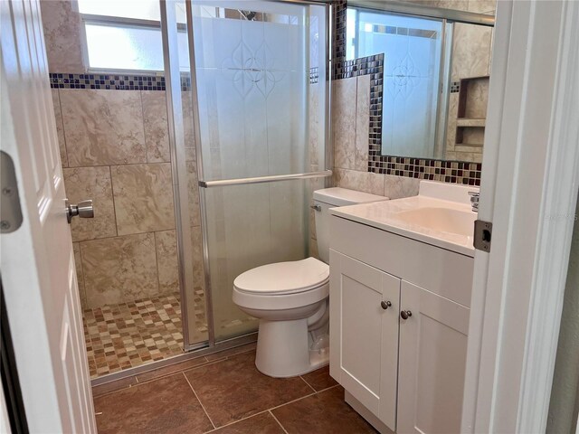 13637 Lagoon Dr, Hudson, FL 34667 - bathroom featuring tile walls, a shower stall, vanity, tile patterned floors, and toilet