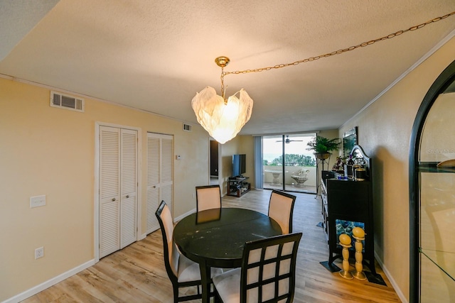 dining space with crown molding, a textured ceiling, and light wood-type flooring