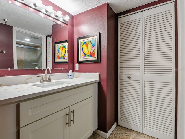 bathroom featuring vanity, an enclosed shower, and a textured ceiling