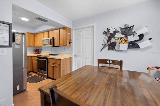 kitchen with appliances with stainless steel finishes and light hardwood / wood-style floors