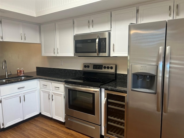 kitchen with white cabinetry, sink, dark stone countertops, beverage cooler, and stainless steel appliances