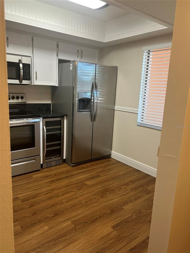 kitchen featuring white cabinetry, appliances with stainless steel finishes, dark hardwood / wood-style floors, a raised ceiling, and beverage cooler