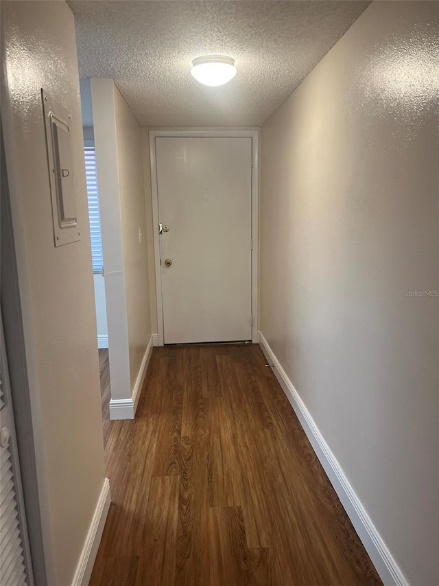 hallway featuring wood-type flooring, electric panel, and a textured ceiling