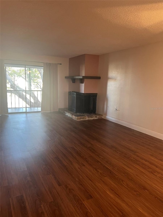 unfurnished living room with dark hardwood / wood-style floors, a stone fireplace, and a textured ceiling