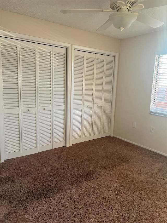 unfurnished bedroom featuring multiple closets, carpet floors, and ceiling fan